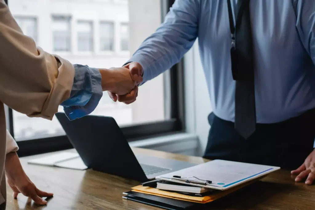 Two people shaking hands at a desk.