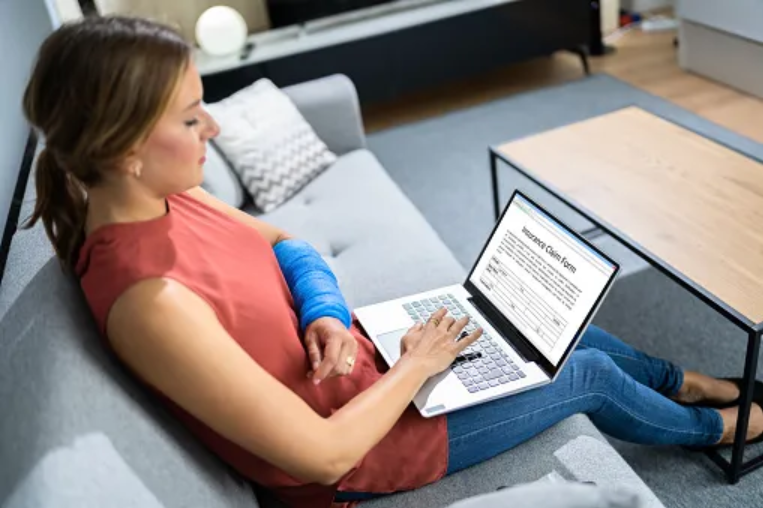 Injured woman working on her laptop with her arm in a cast.