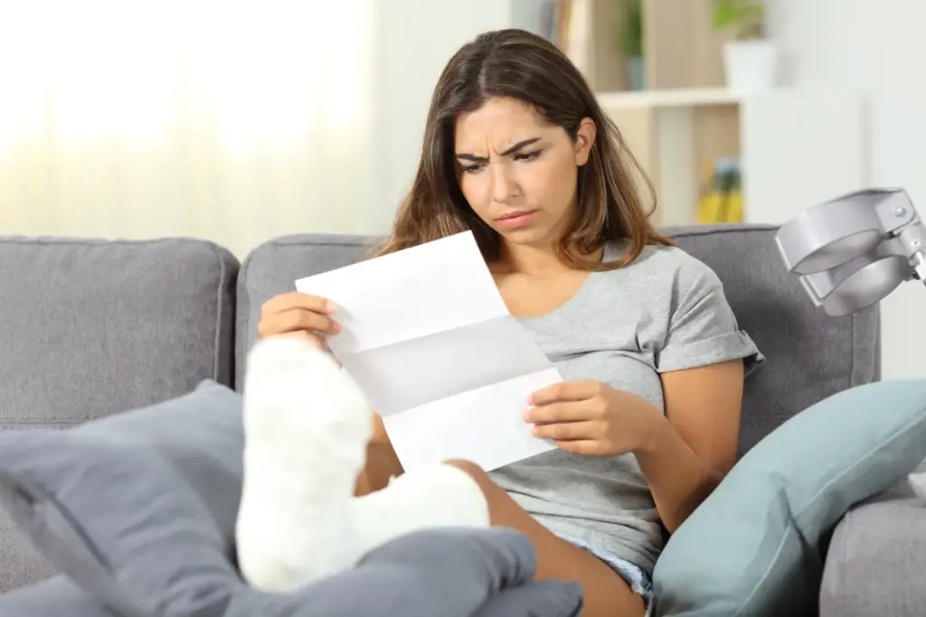 Woman with her leg in a cast looking at her medical bills.