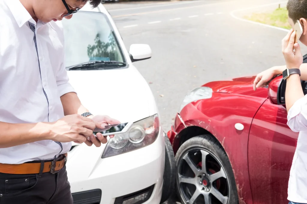 Two male drivers speaking on their phones after an accident.