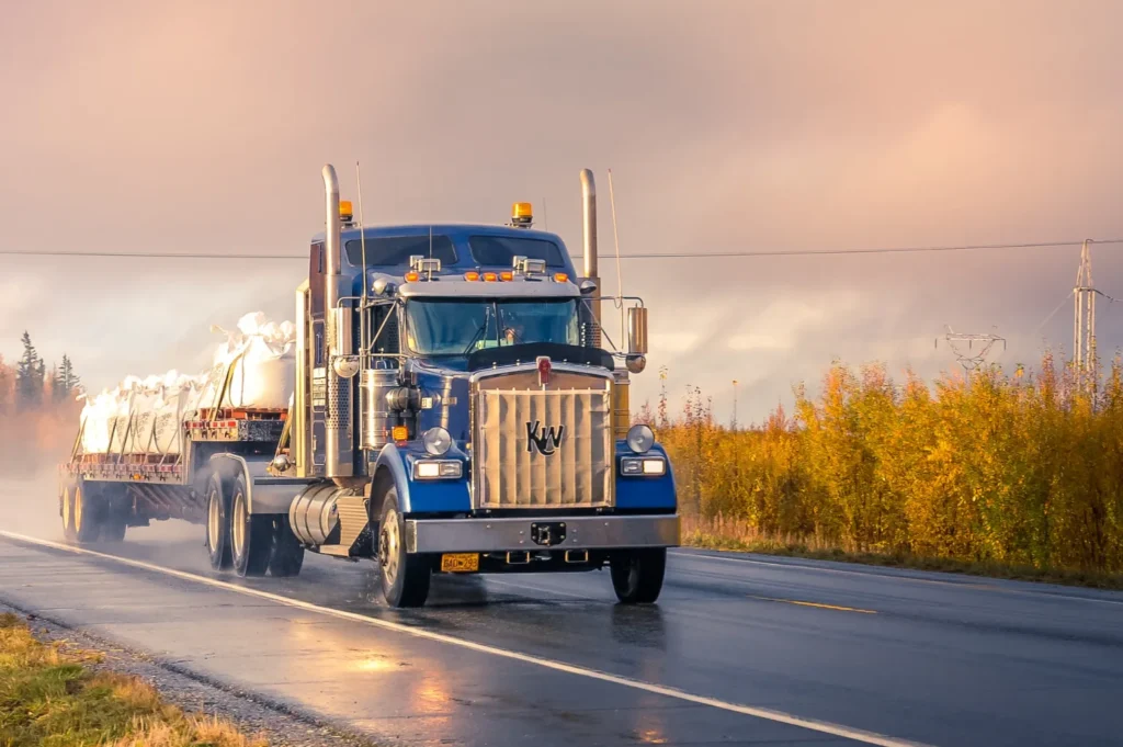 A blue semi truck driving down the highway.