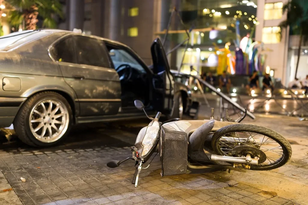 A motorcycle on its side in the street after hitting a car.