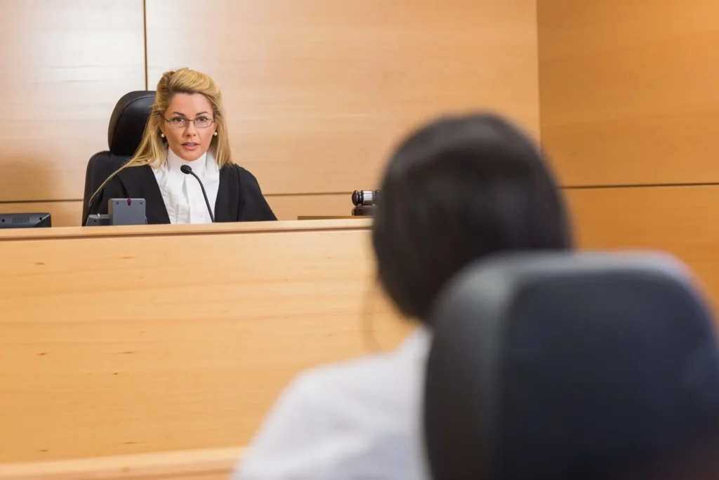 Person sitting in front of a judge in a court room.