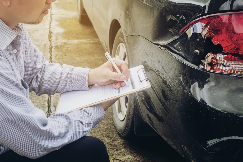 Person documenting damage to a car.