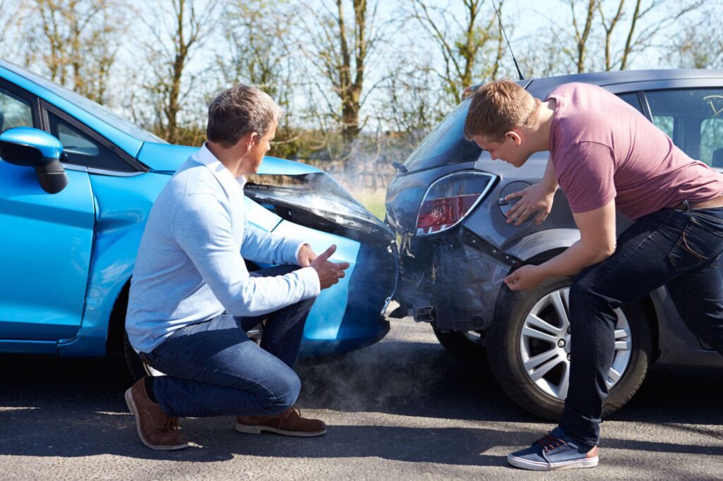 Two people talking in front of a car that hit the back of another car. 