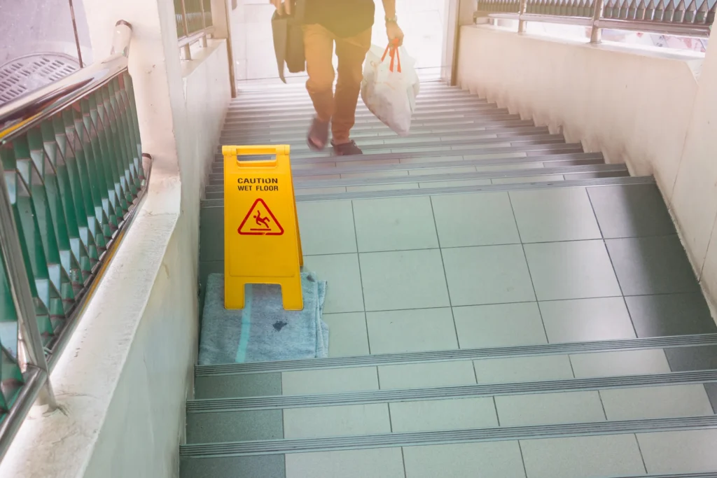 Someone walking up the stairs where there is a caution sign. 