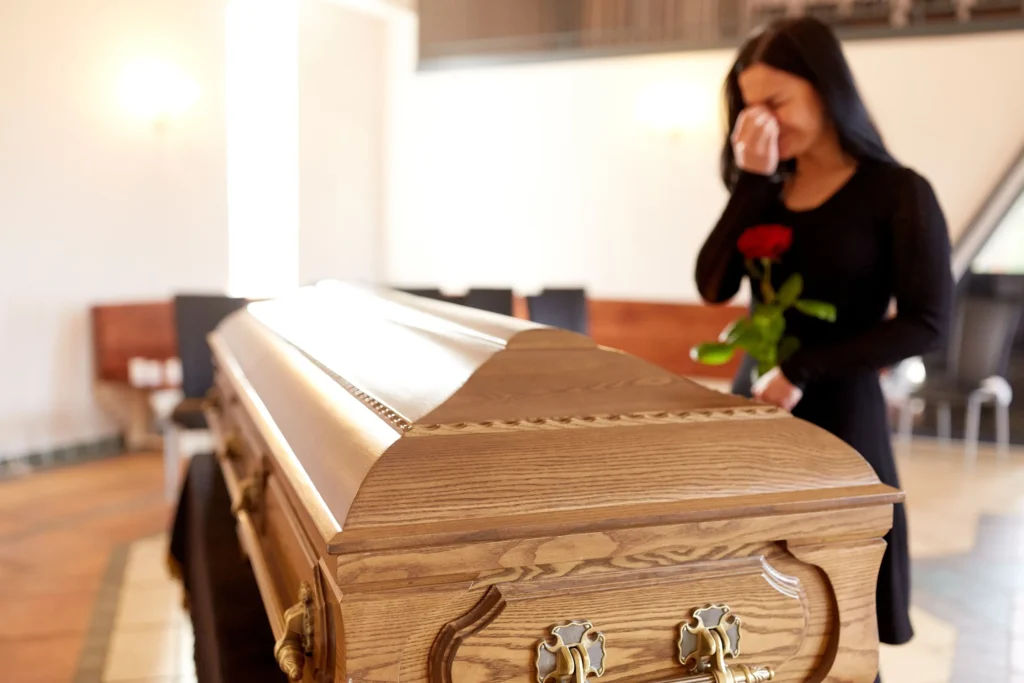 A woman grieving by a casket. 