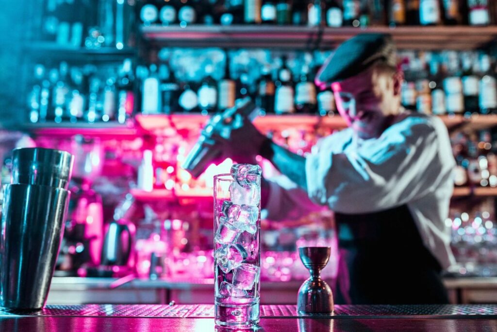 A bartender making a drink at an establishment.