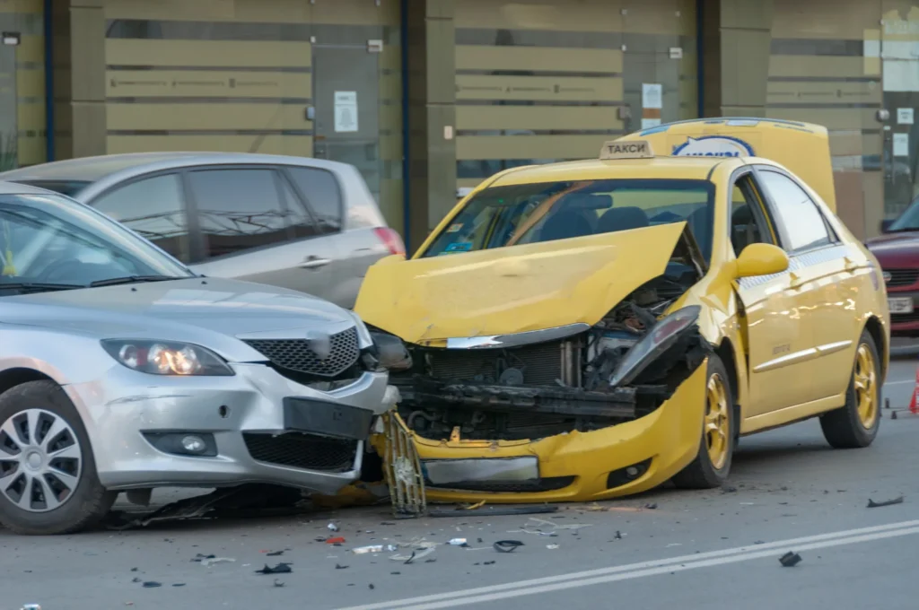 Damaged silver car and yellow taxi after a collision, representing guidance on dealing with insurance companies after a car accident in Eagle Pass.